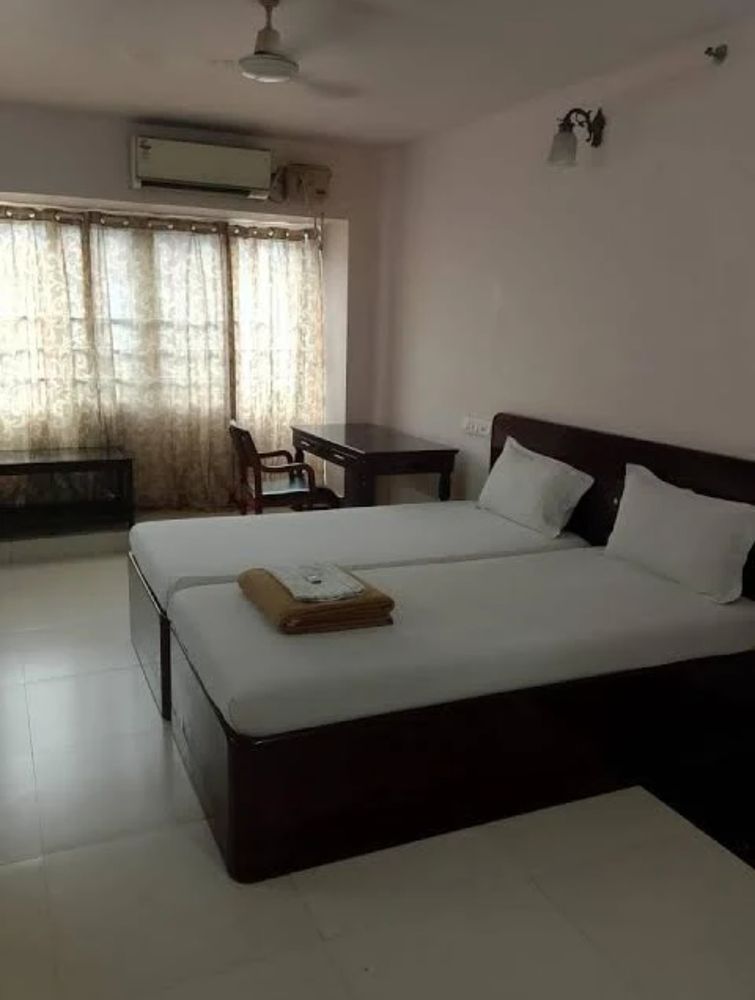 Twin AC room at Hotel Sunnys with two beds, a writing desk and a wall AC unit