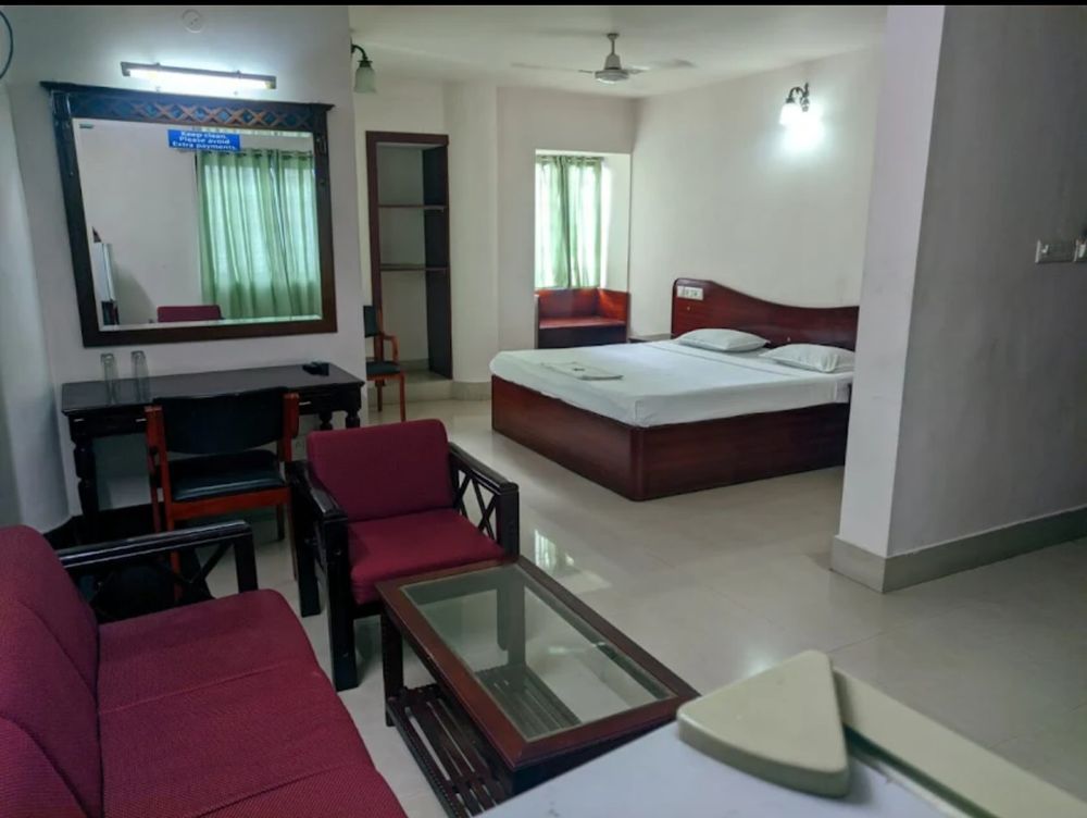 Suite at Hotel Sunnys with a double bed, a red sofa and armchairs around a glass coffee table